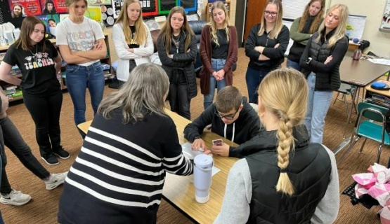 A teacher is pictured working with a students while Teaching Professions students observe her interaction with the student. 