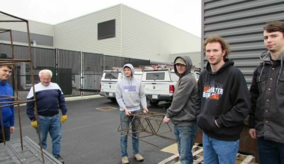 Welding students load the sturdy tomato cages they welded for a community service project as Kip Wright (second from left) gives direction. 
