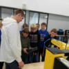 An eighth grader tries the teach pendant of a FANUC robot during Tri Star tours. 