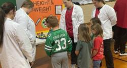 Med Prep students talk to elementary students about height and weight at a Health Fair. 