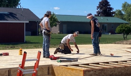 Senior construction students measure subfloor material which will go over the floor joists on the foundation of the 2022-23 Tri Star house. 
