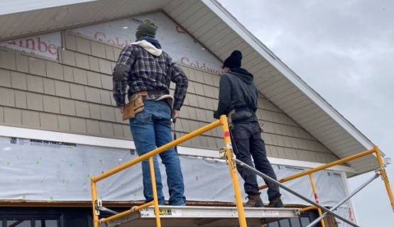 Senior construction students on scaffolding work to add siding to the 2023 Tri Star house. 