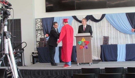 A student in cap and gown walks the Tri Star graduation stage to receive their career passport during graduation activities May 13th. 