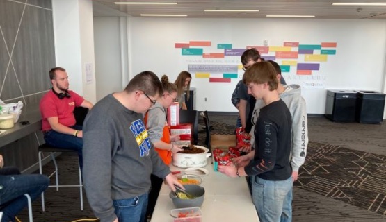 Students are pictured holding a bag of Doritos as Career Pathway students fill it with toppings to make a walking taco. 