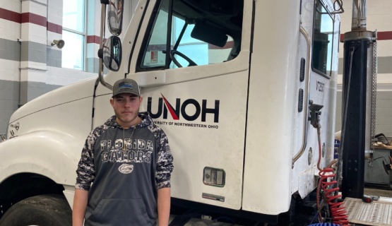 Senior Titus Hoover standing next to the cab of a UNOH semi. 