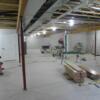 Unfinished basement with safe room, utilities and shelving, egress window, and staircase to garage.: Gallery Image 1 