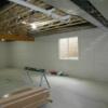 Unfinished basement with safe room, utilities and shelving, egress window, and staircase to garage.: Gallery Image 3 