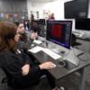 An Interactive Media senior and visiting sophomore working on a computer.: Gallery Image 1 