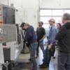 Mitch Knous, adult machining instructor (in light blue shirt) , teaches a group of students basic skills on a Haas CNC lathe. 