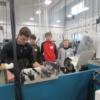 A precision machining senior is seen showing a trio of sophomores how a lathe works.: Gallery Image 1 