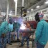 Adult students carefully watch instructor Joe Braun as he demonstrates a welding technique.: Gallery Image 1 
