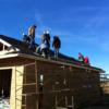 Seniors crawling on the roof of the Tri Star house as they shingle it. 