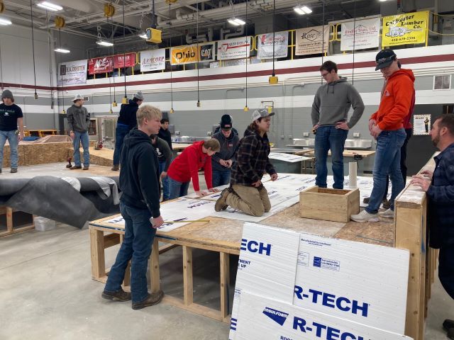 Jon Plattner (far right) talks with a group of construction students as they work on one of the roof mock-ups.: Featured Image 1 
