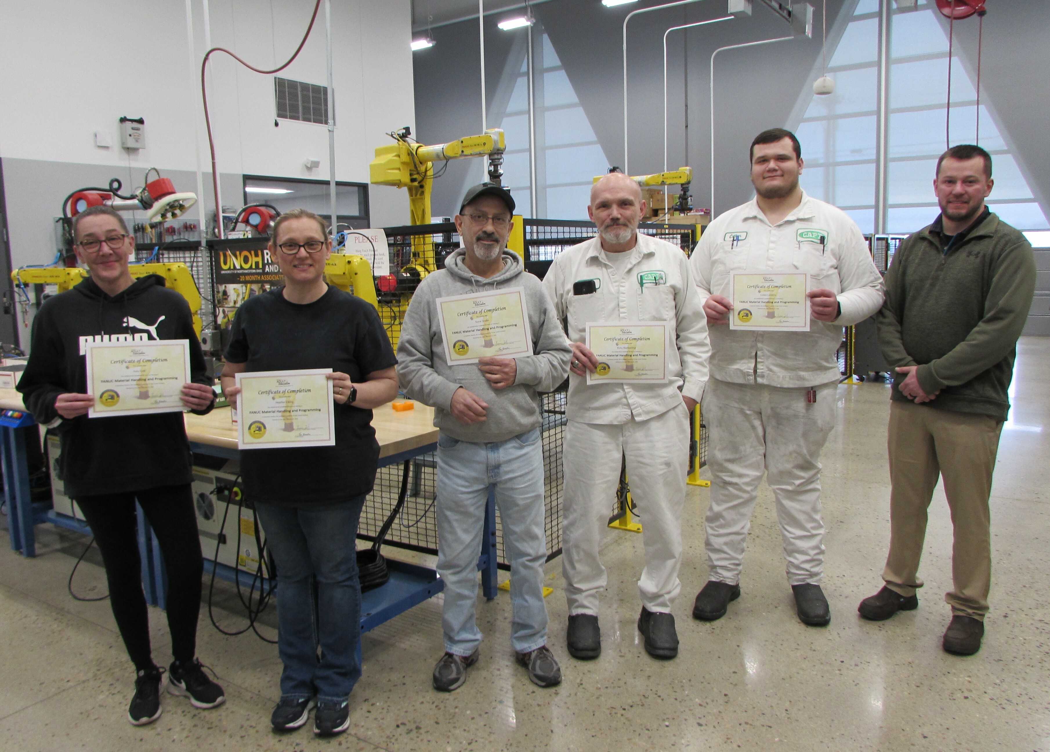 Adult students pose with their certificates and instructor Luke Zinc in the robotics lab.: Featured Image 1 