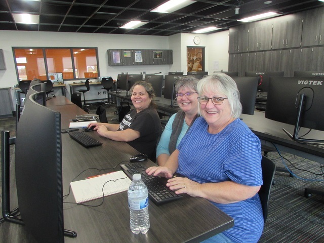 Adult students and instructor sitting at a bank of computers.: Featured Image 1 
