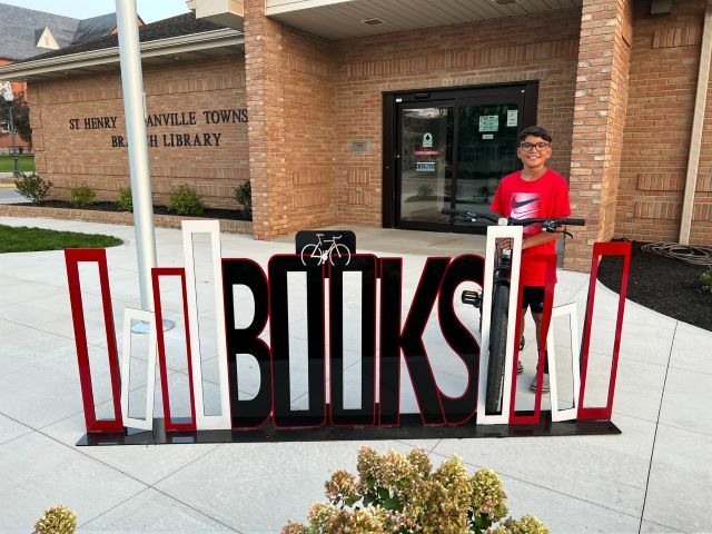Jonny Gonzalez parks his bike in the new bike rack in front of the St. Henry Community Library.: Featured Image 1 